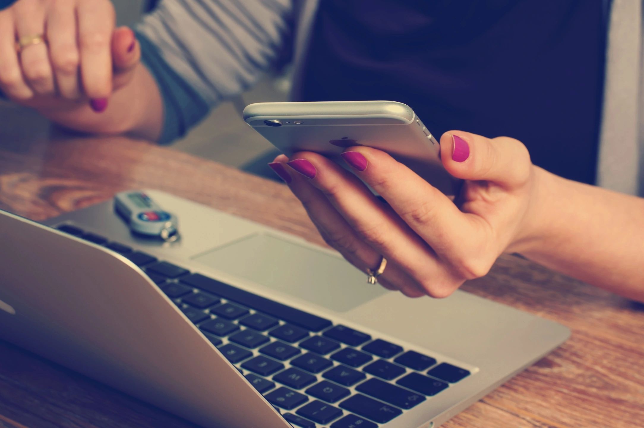 Woman holding a phone while reading about blogs on her laptop.